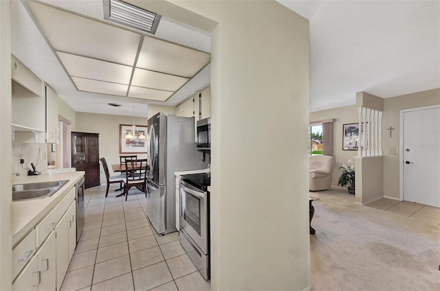 kitchen with appliances with stainless steel finishes, light tile patterned floors, sink, and white cabinetry