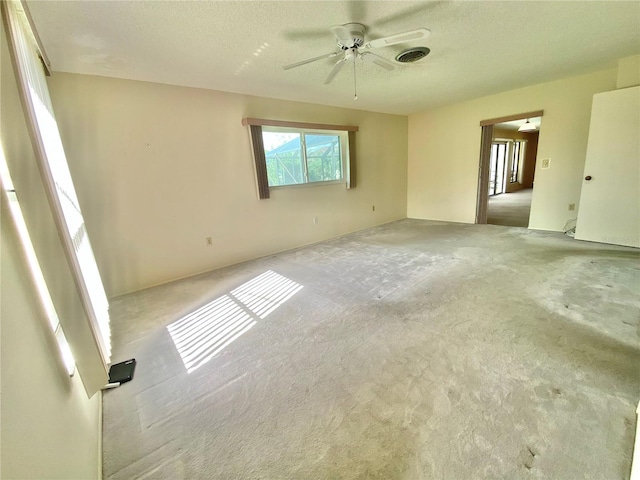 empty room featuring a textured ceiling, ceiling fan, and light colored carpet