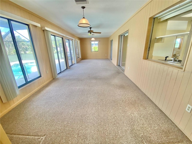 carpeted empty room with ceiling fan and wooden walls