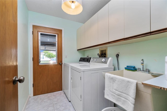 laundry room featuring cabinets, a textured ceiling, sink, light tile patterned floors, and washing machine and clothes dryer