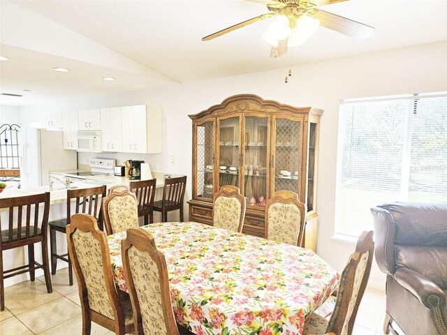 dining room with light tile patterned floors, vaulted ceiling, and ceiling fan