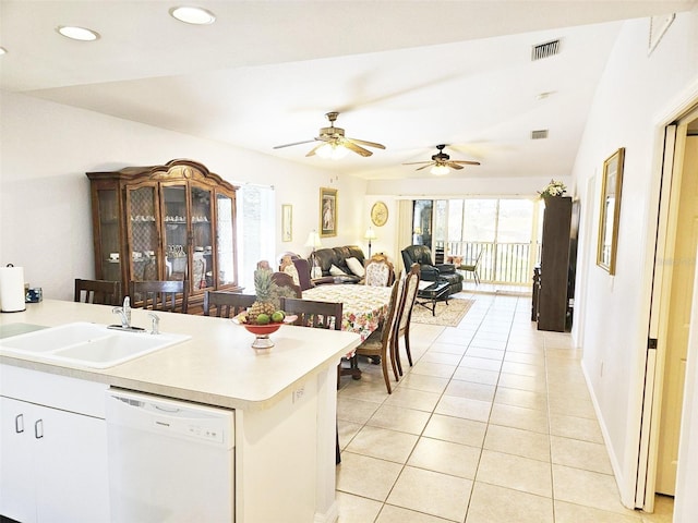 kitchen featuring a breakfast bar, lofted ceiling, white dishwasher, sink, and light tile patterned flooring