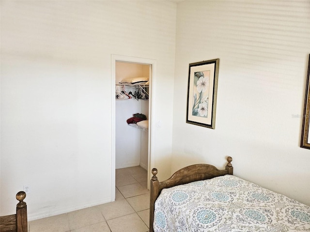 bedroom with a spacious closet, light tile patterned floors, and a closet