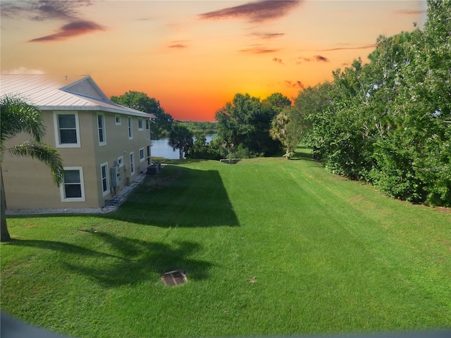 yard at dusk featuring a water view