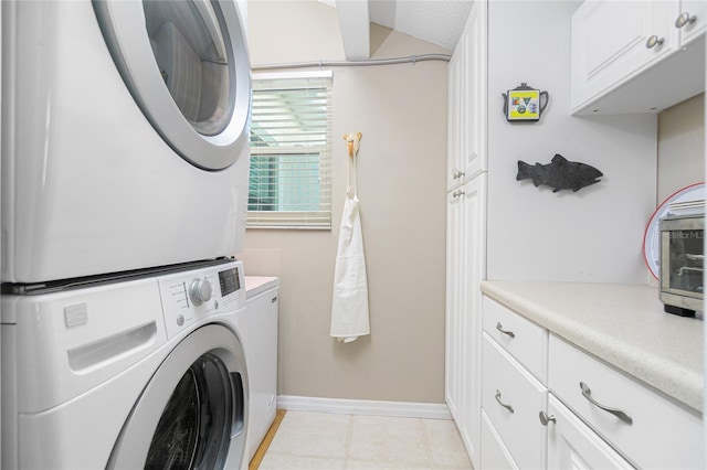 laundry area with a textured ceiling, cabinets, and stacked washer / dryer