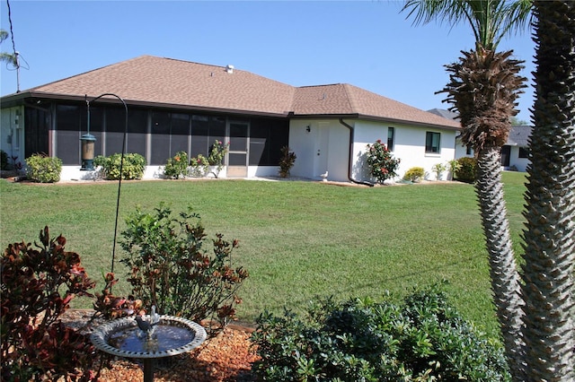 rear view of property featuring a lawn and a sunroom