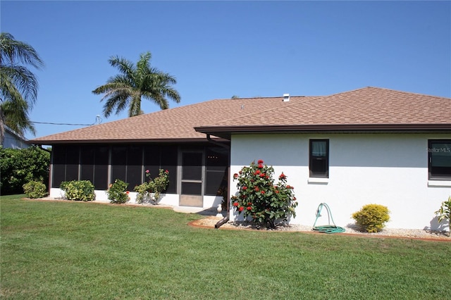 rear view of house featuring a sunroom and a yard