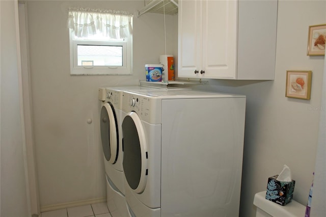 washroom featuring cabinets, washing machine and dryer, and light tile patterned floors