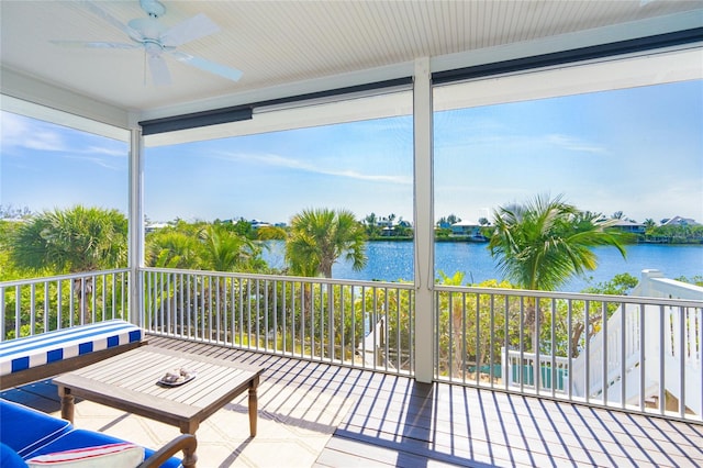 unfurnished sunroom with ceiling fan and a water view