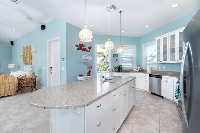 kitchen with appliances with stainless steel finishes, a kitchen island with sink, light tile patterned floors, decorative light fixtures, and sink