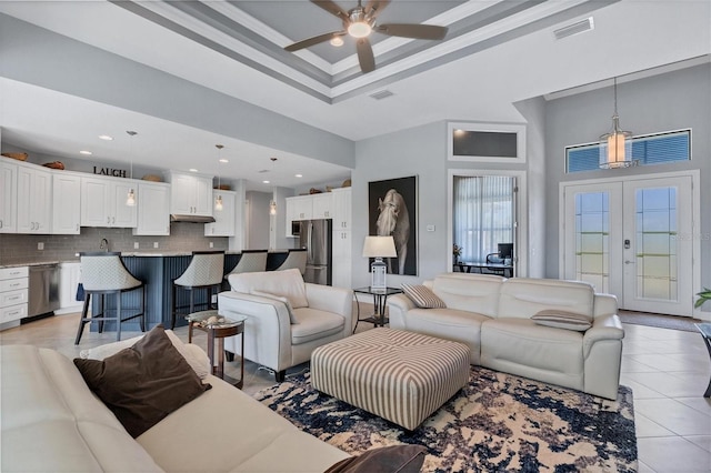 tiled living room with french doors, ceiling fan, sink, a towering ceiling, and a tray ceiling