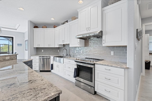 kitchen with light tile floors, light stone counters, appliances with stainless steel finishes, tasteful backsplash, and white cabinetry