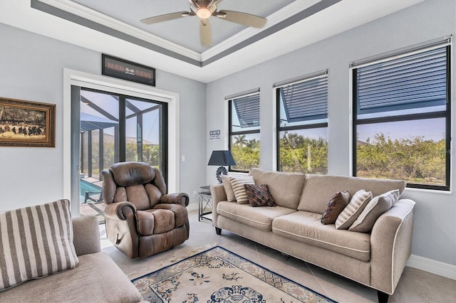 living room featuring ornamental molding, a healthy amount of sunlight, ceiling fan, and a tray ceiling