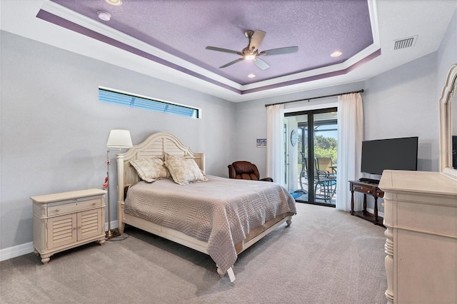 bedroom with light colored carpet, ceiling fan, access to outside, a tray ceiling, and a textured ceiling