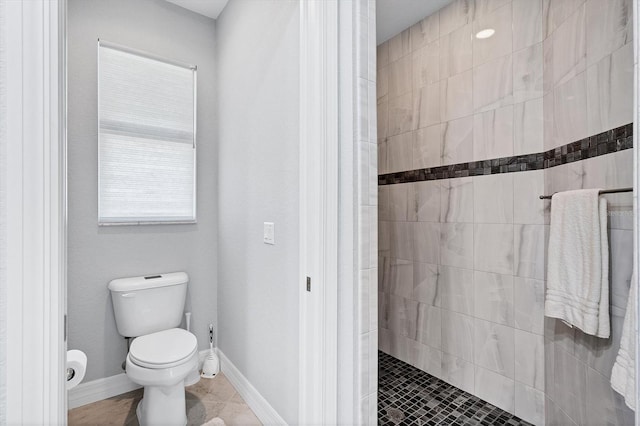 bathroom featuring tile flooring, toilet, and tiled shower