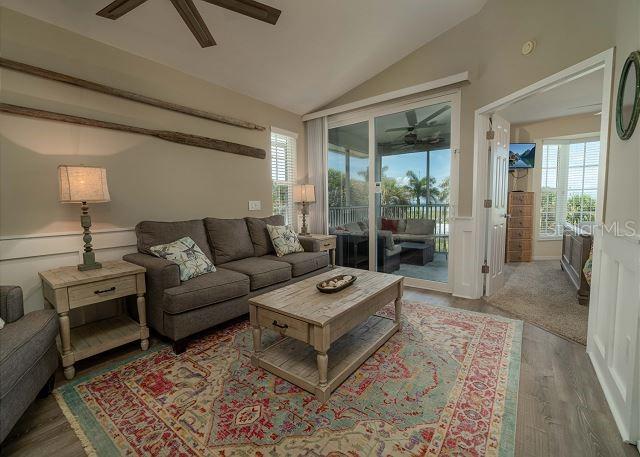 living room with vaulted ceiling, ceiling fan, and light hardwood / wood-style flooring