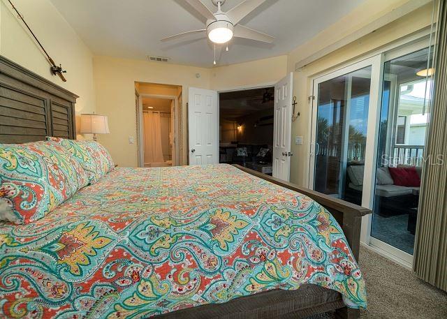 bedroom featuring access to outside, dark carpet, and ceiling fan