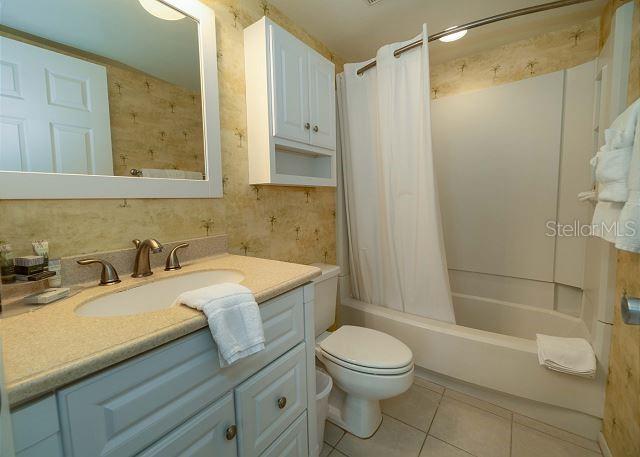 full bathroom with shower / bath combo, toilet, vanity, and tile flooring