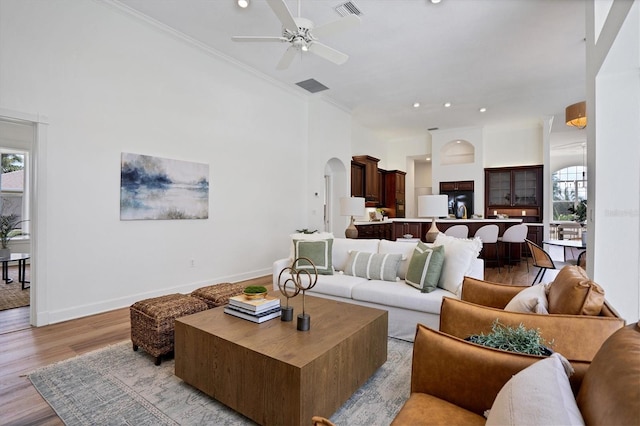 living room featuring crown molding, ceiling fan, a wealth of natural light, and light hardwood / wood-style flooring