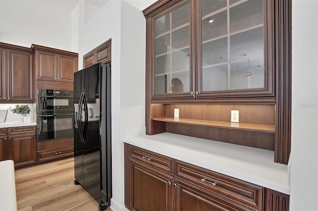 kitchen featuring dark brown cabinets, light wood-type flooring, and black appliances