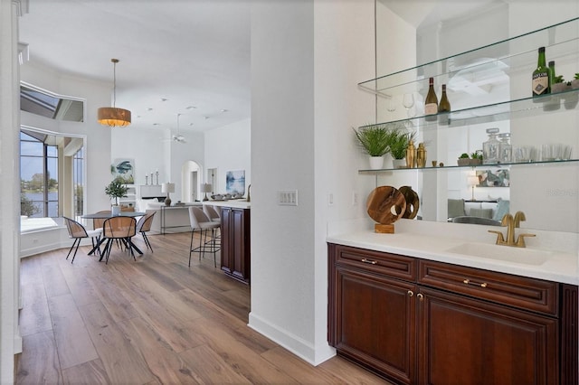 bar with pendant lighting, sink, and light wood-type flooring