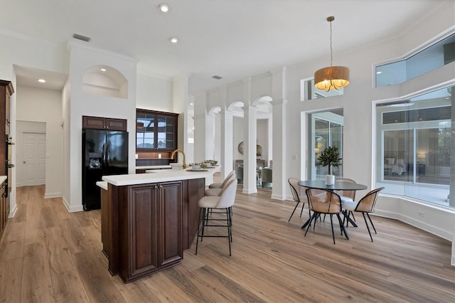 kitchen with hanging light fixtures, a chandelier, black fridge with ice dispenser, and light wood-type flooring