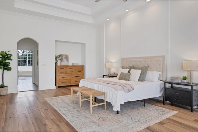 bedroom featuring light hardwood / wood-style floors, ornamental molding, and a high ceiling