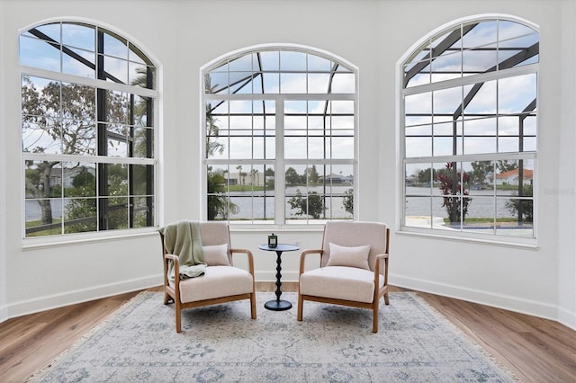 sitting room with dark hardwood / wood-style floors, a healthy amount of sunlight, and a water view