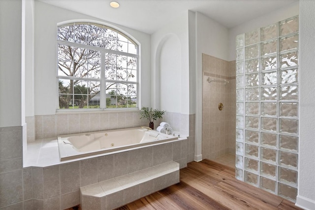 bathroom featuring wood-type flooring, plus walk in shower, and a wealth of natural light