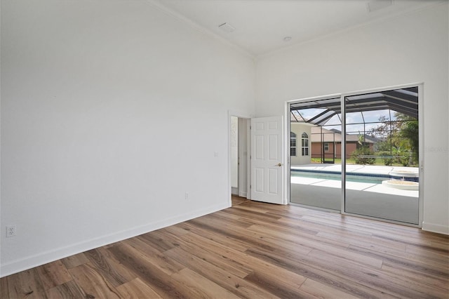 empty room featuring light hardwood / wood-style flooring, a towering ceiling, and crown molding