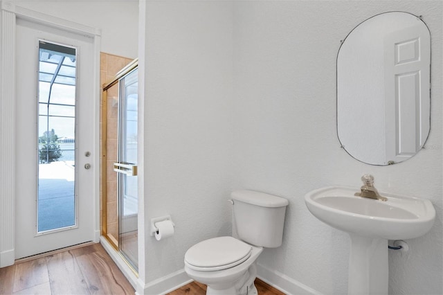 bathroom with toilet, a shower with door, and hardwood / wood-style floors