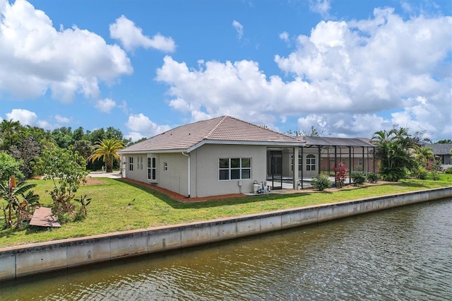 rear view of house with a lawn, a water view, a patio, and a lanai