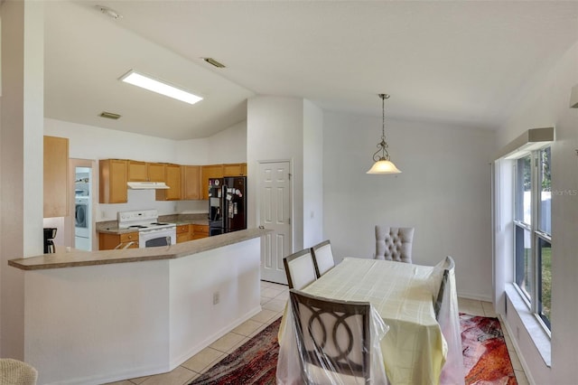 kitchen featuring lofted ceiling, hanging light fixtures, white electric stove, light tile floors, and black fridge