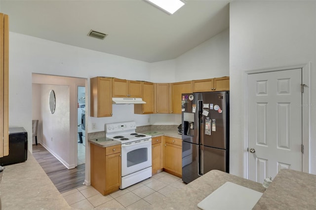 kitchen with high vaulted ceiling, washer / dryer, white electric stove, light hardwood / wood-style floors, and stainless steel refrigerator with ice dispenser