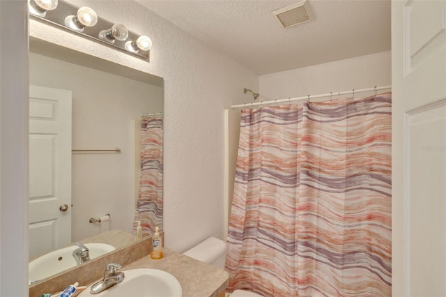 bathroom featuring toilet, vanity, and a textured ceiling