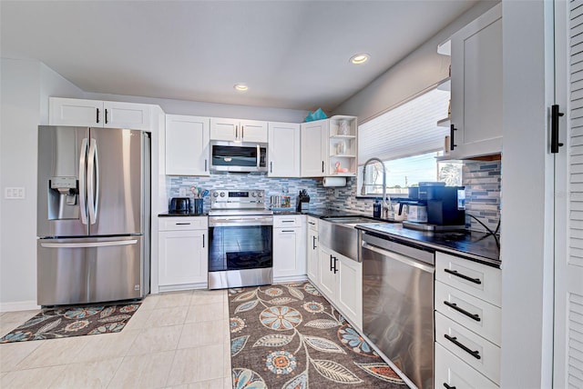 kitchen featuring light tile flooring, appliances with stainless steel finishes, white cabinetry, backsplash, and sink