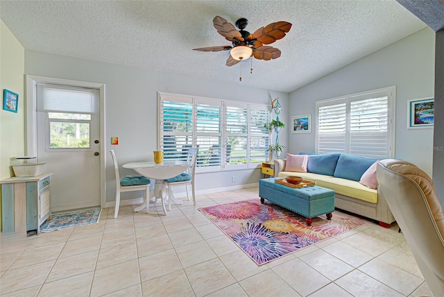 living room with a textured ceiling, ceiling fan, light tile floors, and lofted ceiling