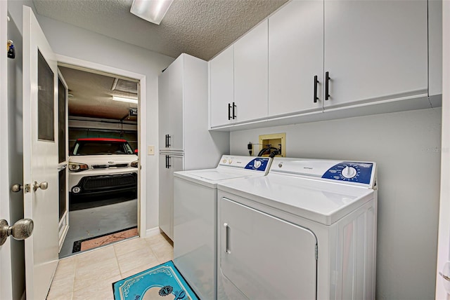 laundry area featuring washer hookup, light tile flooring, a textured ceiling, cabinets, and washer and dryer