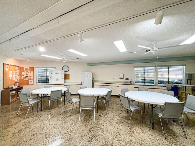 dining area featuring ceiling fan and a textured ceiling