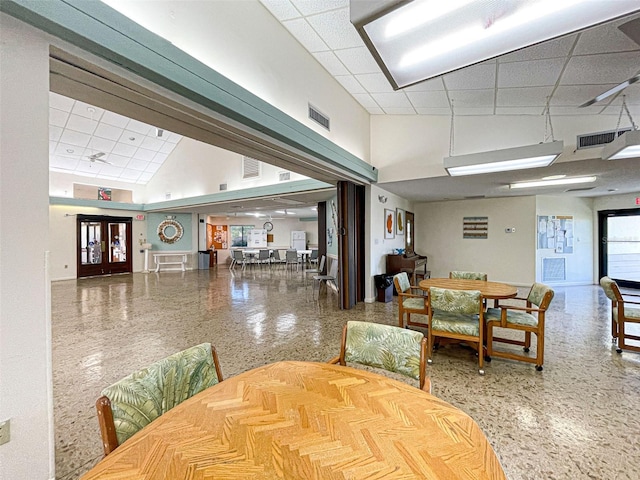 dining space featuring a paneled ceiling, french doors, and a high ceiling