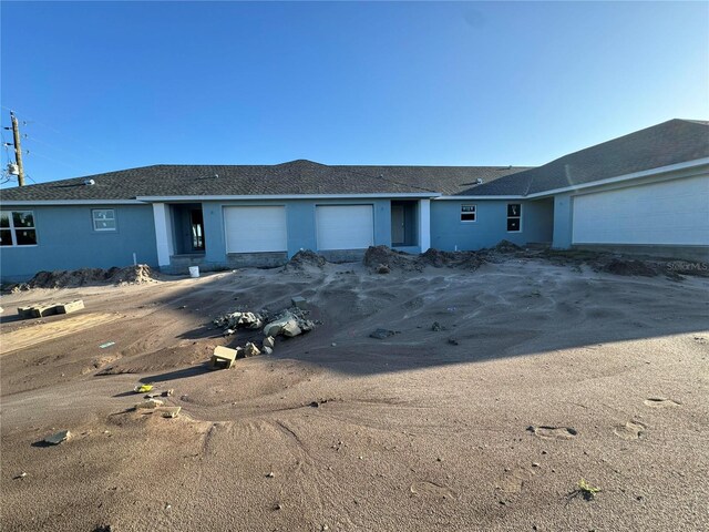 ranch-style home featuring a garage and stucco siding