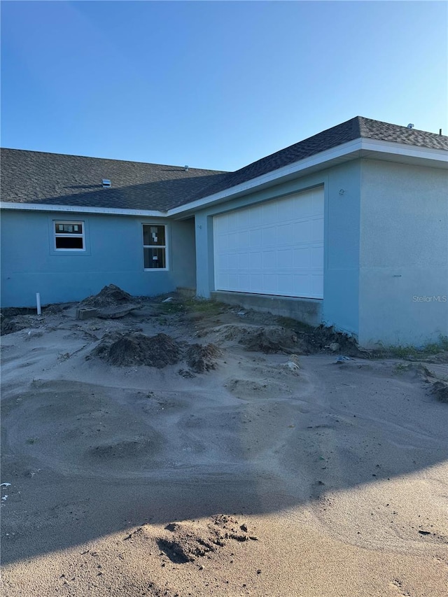 view of home's exterior featuring an attached garage and roof with shingles