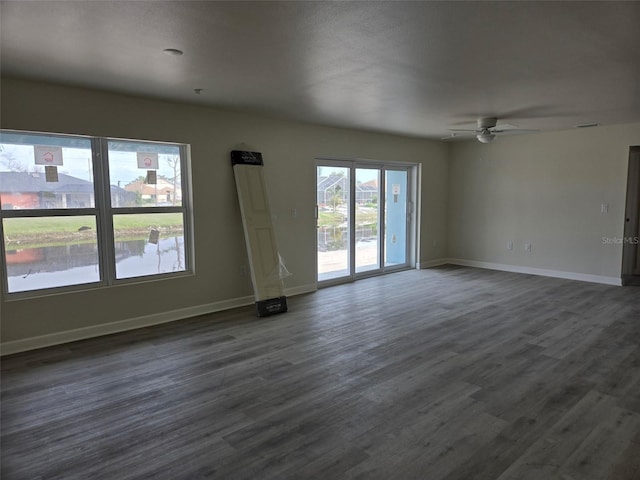 empty room featuring dark wood-style floors, baseboards, and a ceiling fan