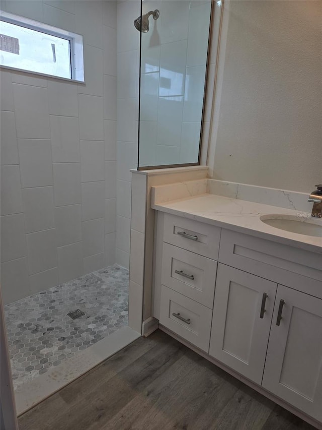 bathroom featuring walk in shower, wood finished floors, and vanity