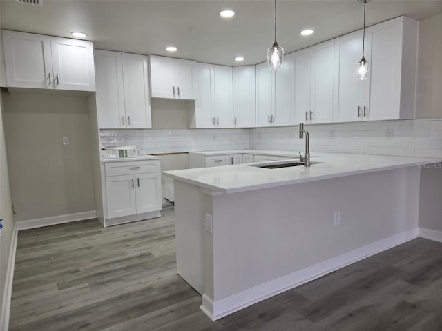 kitchen with a peninsula, a sink, and white cabinetry