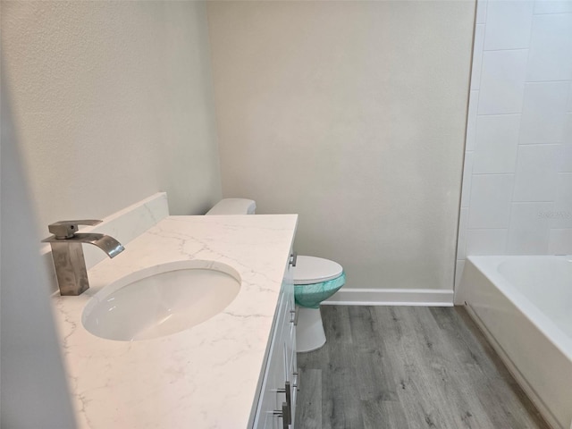 full bath with toilet, baseboards, wood finished floors, and vanity