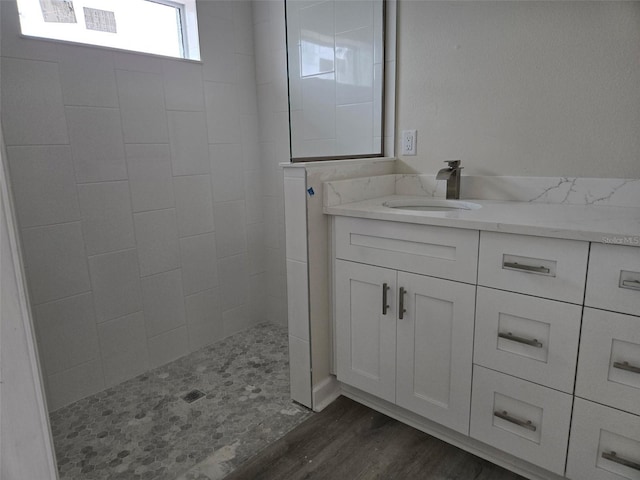 bathroom featuring a walk in shower, wood finished floors, and vanity