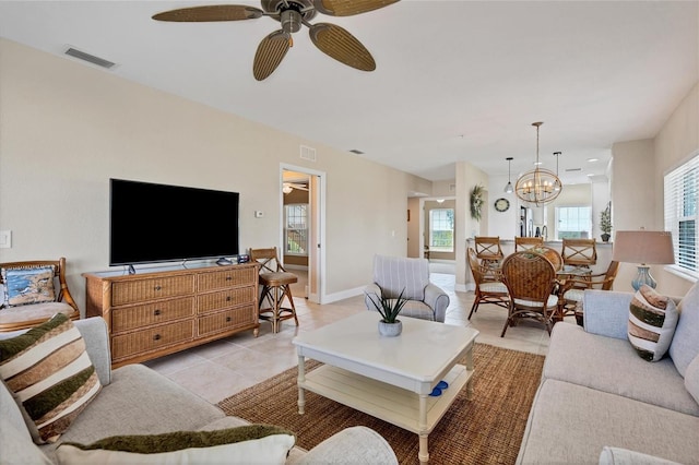 living room with light tile floors and ceiling fan with notable chandelier