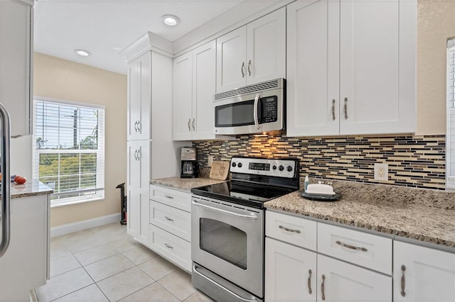 kitchen featuring backsplash, light tile flooring, appliances with stainless steel finishes, white cabinets, and light stone counters