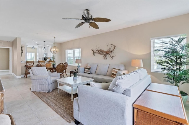 tiled living room featuring ceiling fan with notable chandelier